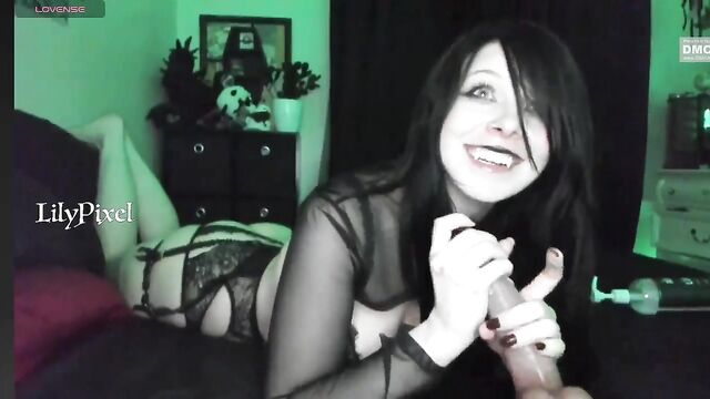 A goth slut licks and sucks a dildo with her feet in the air